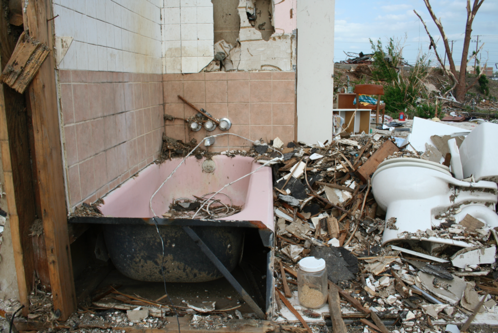 an image of a decimated home, with only the bathtub left intact. 