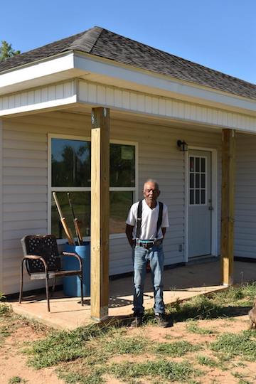 A tornado survivor stands outside his new home, provided by AWFUMC.