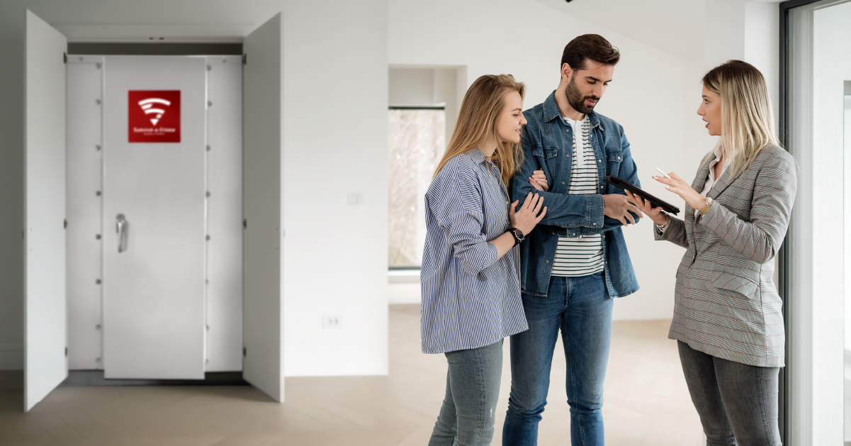 Homebuyers reviewing documents with a real estate agent while touring a house with an in-home tornado shelter.