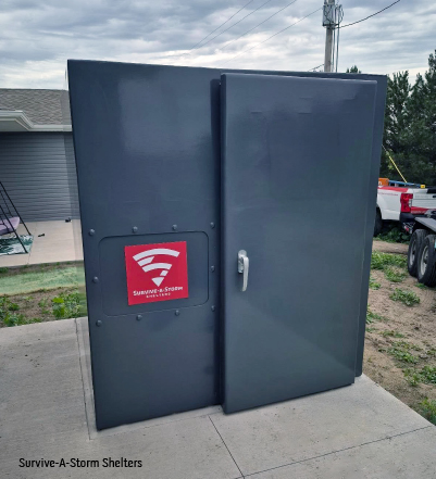 storm shelter for homes Above-ground residential steel storm shelter installed on a slab, beside a home.