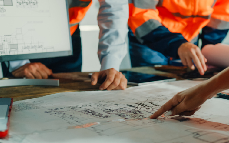 Project team reviewing engineering drawings during the planning and design phase of a commercial tornado shelter installation.